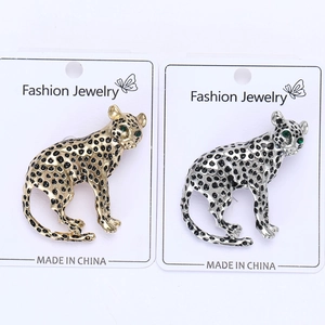Detail of leopard brooches in gold and silver finish with green gemstone eyes