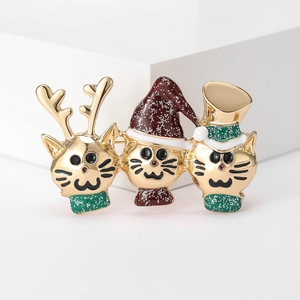 Détail macro de trois broches chats de Noël en émail avec chapeaux festifs et paillettes