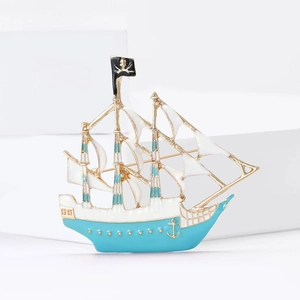 Nautical pirate ship brooch with blue and white enamel and gold trim on white podiums