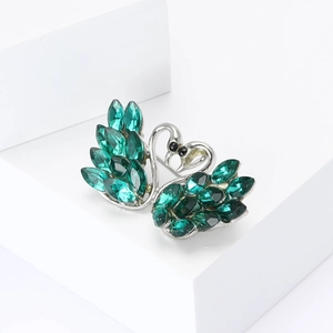 Elegant silver-toned twin swan brooch with shimmering emerald green marquise crystals