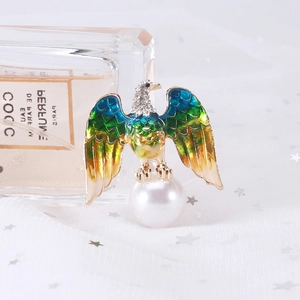 Close-up of eagle brooch featuring enamel wings, crystal head and a large white pearl base