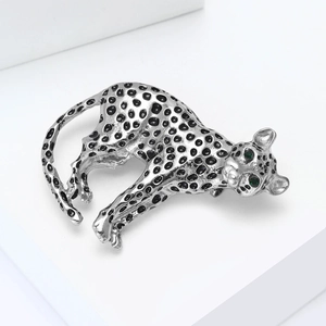 Macro shot of silver leopard brooch with black enamel spots and green crystal eyes