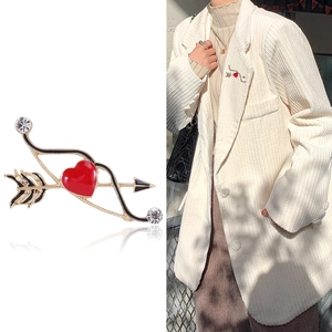 Spilla a forma di freccia e cuore in lega dorata con smalto e strass su sfondo bianco e modella