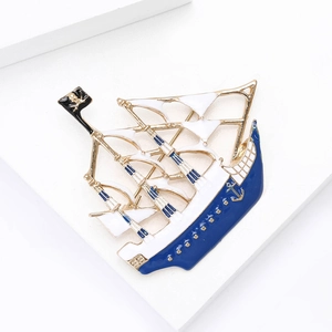 Detail shot of a vintage pirate ship brooch with blue enamel and golden metal accents