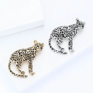 Elegant gold and silver leopard brooches with black enamel spots and green gemstone eyes