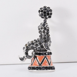 Close-up of seal brooch with black rhinestones and orange enamel detail on silver base