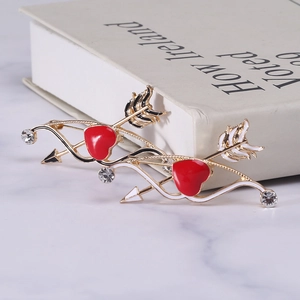 Spille a freccia di Cupido con cuore in smalto rosso e cristalli su libro vintage