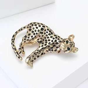 Detail of vintage gold leopard brooch with black enamel spots and green gemstone eyes