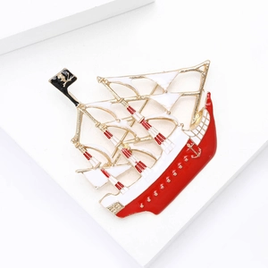 Detailed close-up of a pirate ship enamel brooch with red hull and white sails