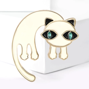 Schattige emaille kattenbroche met groene edelstenen ogen en goud op witte sokkel