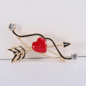 Dettaglio della spilla a freccia di Cupido dorata con cuore smaltato rosso e cristalli