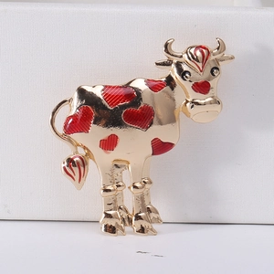 Detail of a golden alloy cow brooch with red enamel hearts and vibrant oil-drop finish