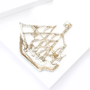 Detail view showing the alloy sailboat brooch back with pin closure on a white platform