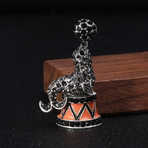 Close-up of a circus seal brooch with rhinestones and orange enamel base details