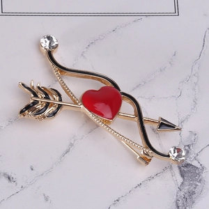 Dettaglio spilla arco di Cupido con cuore in smalto rosso e cristalli su fondo marmo