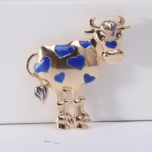 Detailed close-up of a gold cartoon ox brooch with blue heart-shaped enamel spots