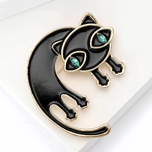 Detail van een elegante zwarte emaille kattenbroche met gouden randen en groene ogen