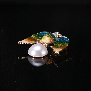 Macro shot of eagle brooch featuring colorful enamel wings and a large half-pearl detail
