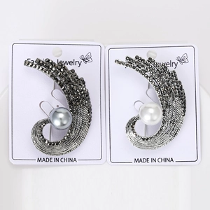 Detailed close-up of fashion feather brooches with grey and white pearls and black rhinestones
