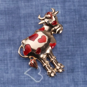 Detailed close-up of a golden alloy cow brooch featuring red heart enamel accents