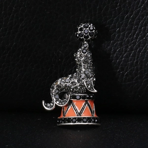 Close-up of seal balancing a ball brooch with black rhinestones and orange enamel base