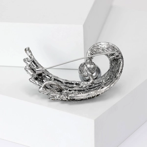 Vintage silver textured feather brooch with dark grey pearl on white podium display