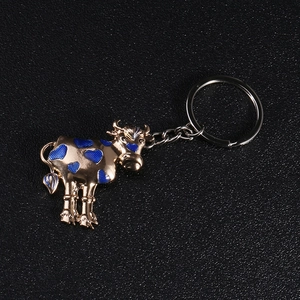 Detailed close-up of a golden cow keychain with blue heart-shaped spots on leather