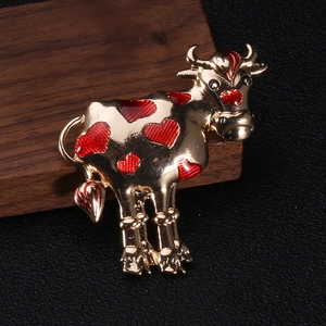 Detailed macro view of the golden ox brooch with red heart enamel patterns on dark wood