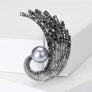Macro shot of vintage pearl feather brooch with black rhinestones on a white pedestal