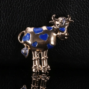 Detailed close-up of golden ox brooch with blue enamel heart pattern on black leather