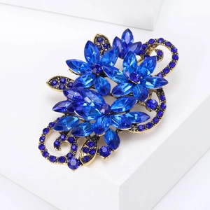 Close-up of vintage gold flower brooch with marquise blue crystals and pavé diamonds