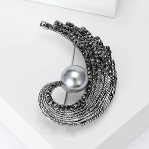 Detail of vintage gun-black C-shape brooch with black rhinestones and large grey pearl
