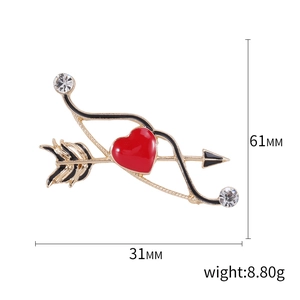 Spilla cuore e freccia con smalto rosso finitura dorata e strass su sfondo bianco