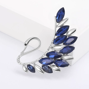 Detailed macro view of silver swan brooch with blue marquise crystals and pavé diamonds