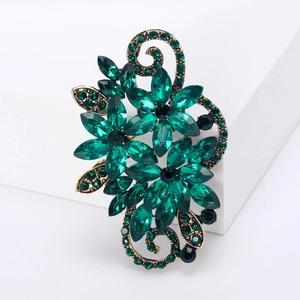 Detail view of vintage flower brooch with green and black crystals on gold base