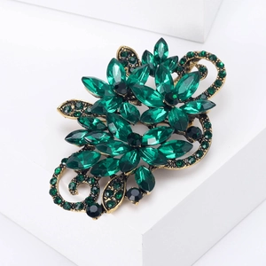 Vintage gold-tone floral brooch with emerald green crystals and black accents