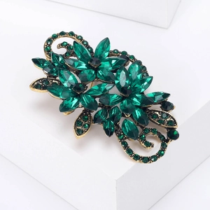 Detailed macro view of vintage emerald crystal floral brooch with antique gold filigree base
