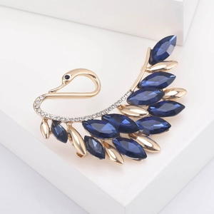 Detailed close-up of a golden swan brooch with blue marquise crystals and white rhinestones
