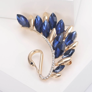 Macro shot of gold swan brooch with blue marquise crystals on white background
