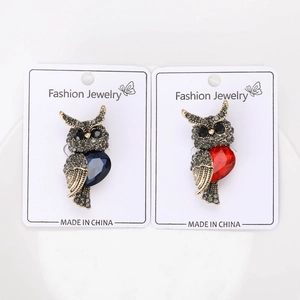 Detailed close-up of owl brooches with red and blue teardrop gems and grey rhinestones
