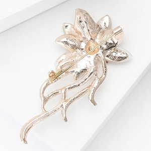 Macro shot of champagne gold flower brooch back with secure safety pin and matte texture