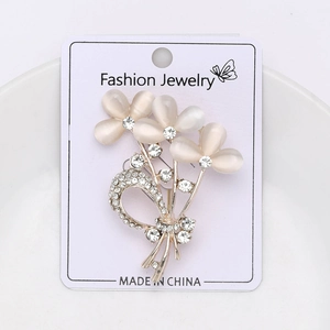 Détail d'une broche bouquet avec pétales d'opale champagne et nœud argenté sur carte
