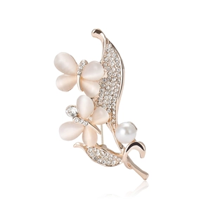 Elegant gold butterfly brooch with cat eye stone, crystals and pearl on white background