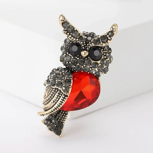 Macro shot of owl brooch featuring a red heart gemstone and vintage gold finish