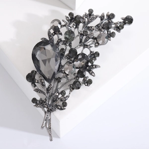 Detail view of a vintage crystal floral brooch with grey rhinestones on a white pedestal