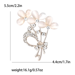 Broche bouquet dorée élégante avec pierres d'opale rose et strass blancs sur fond blanc