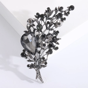 Vintage crystal floral brooch with teardrop grey gemstone and black rhinestones on a stand