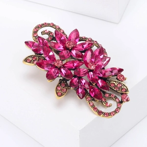 Macro view of vintage gold flower brooch with magenta crystals and intricate rhinestones