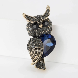 Macro shot of owl brooch featuring blue heart crystal and vintage gold plating
