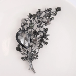 Detailed macro of vintage crystal brooch with grey stones on elegant white ceramic plate